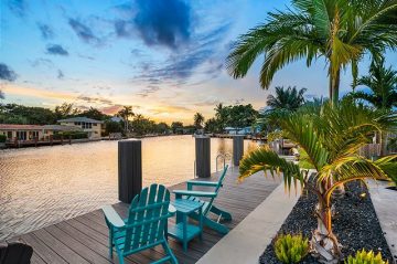 two teal adirondack chairs on the deck facing the sunset