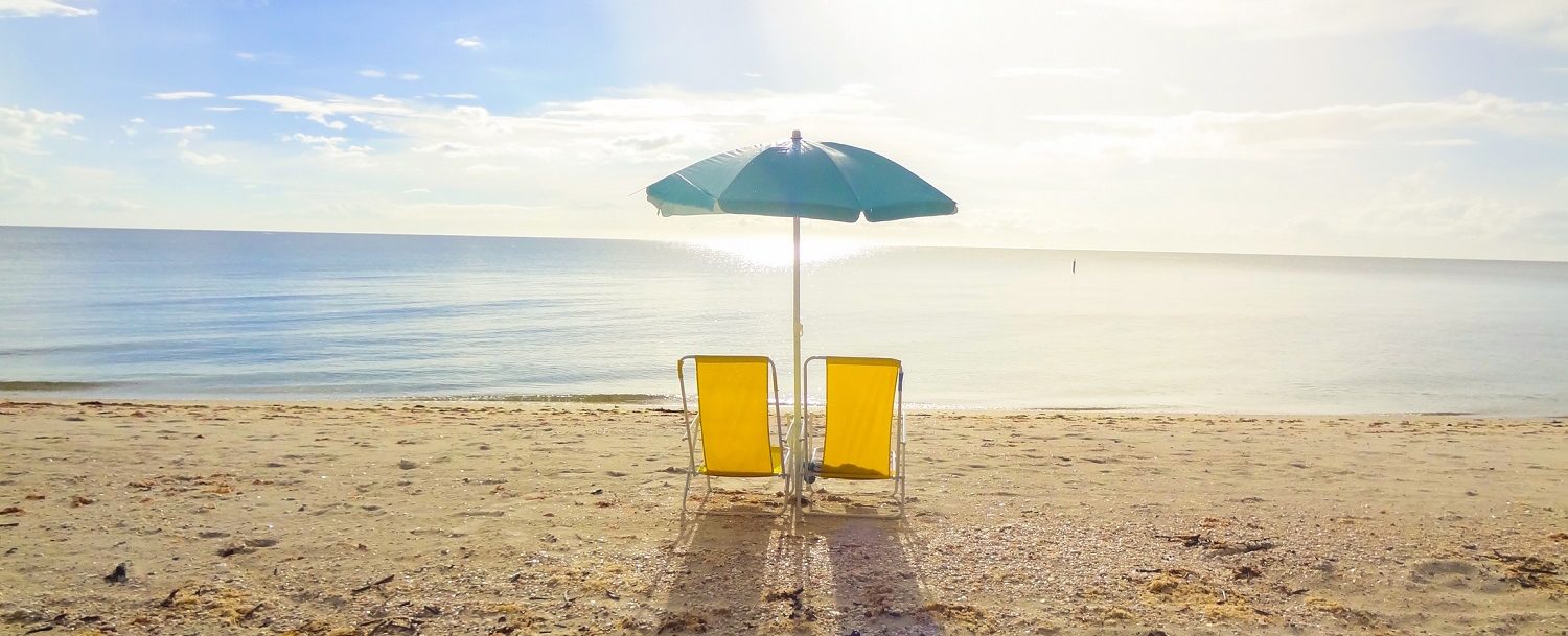 two yellow beach chairs and blue umbrella on the beach