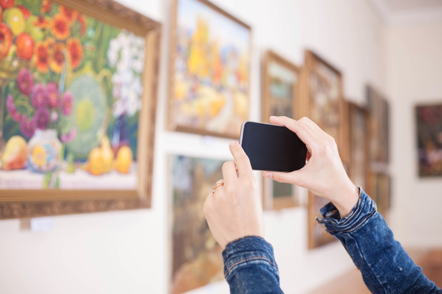 Woman photograph a painting at an exhibition of the art gallery.