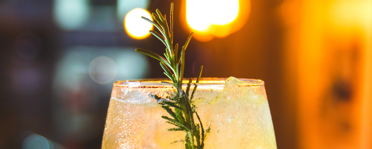 yellow cocktail with a sprig of rosemary